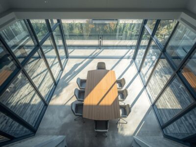 Modern meeting room inside a residential or mixed-use building, conference table, chairs, glass walls, natural light, minimal interior design, clean and professional, realistic interior photography